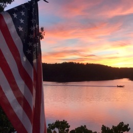 an American flag with a lake and sunset
