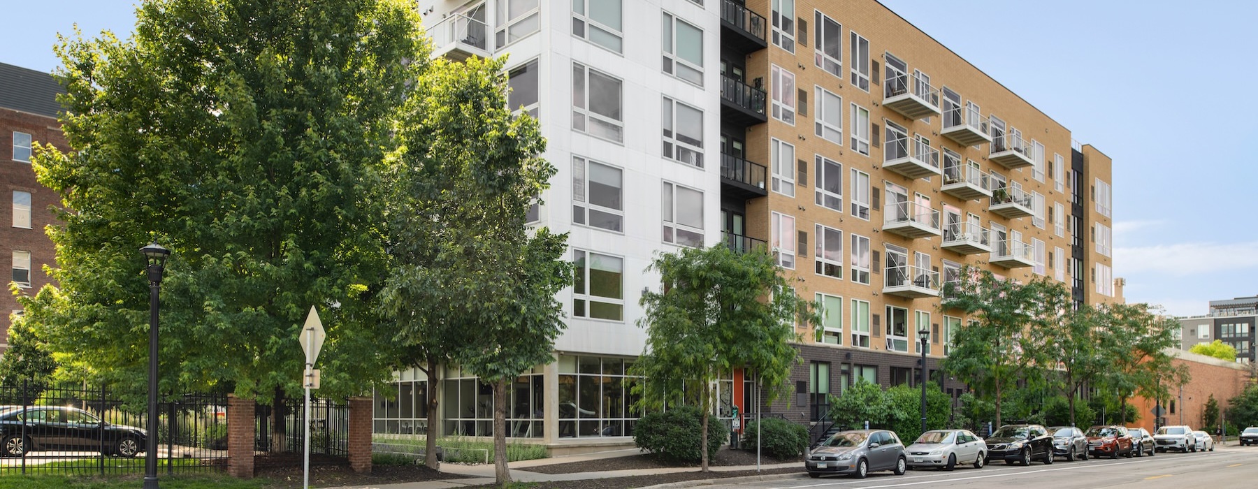 a street with cars and trees by a building